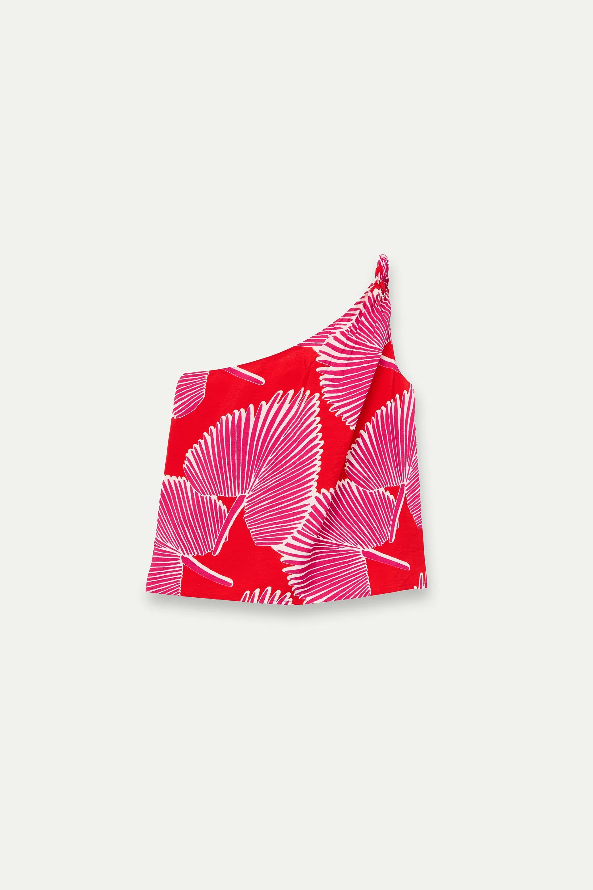Top monospalla con stampa di palme rosa e panna su fondo rosso, fotografato disteso senza modella